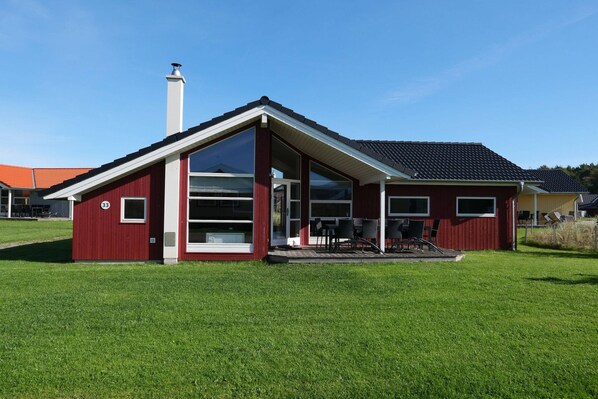 Un edificio rojo con un amplio ventanal, una chimenea y un área de asientos cubierta al aire libre.