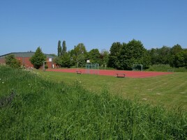 A sports field with a running track, goalposts, and a building in the background.