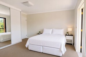A bedroom with a large bed, a nightstand with a lamp, a small potted plant, and a sliding door leading to a balcony. - Peaceful 1BDR Private Stay in Chiswick (Chiswick)