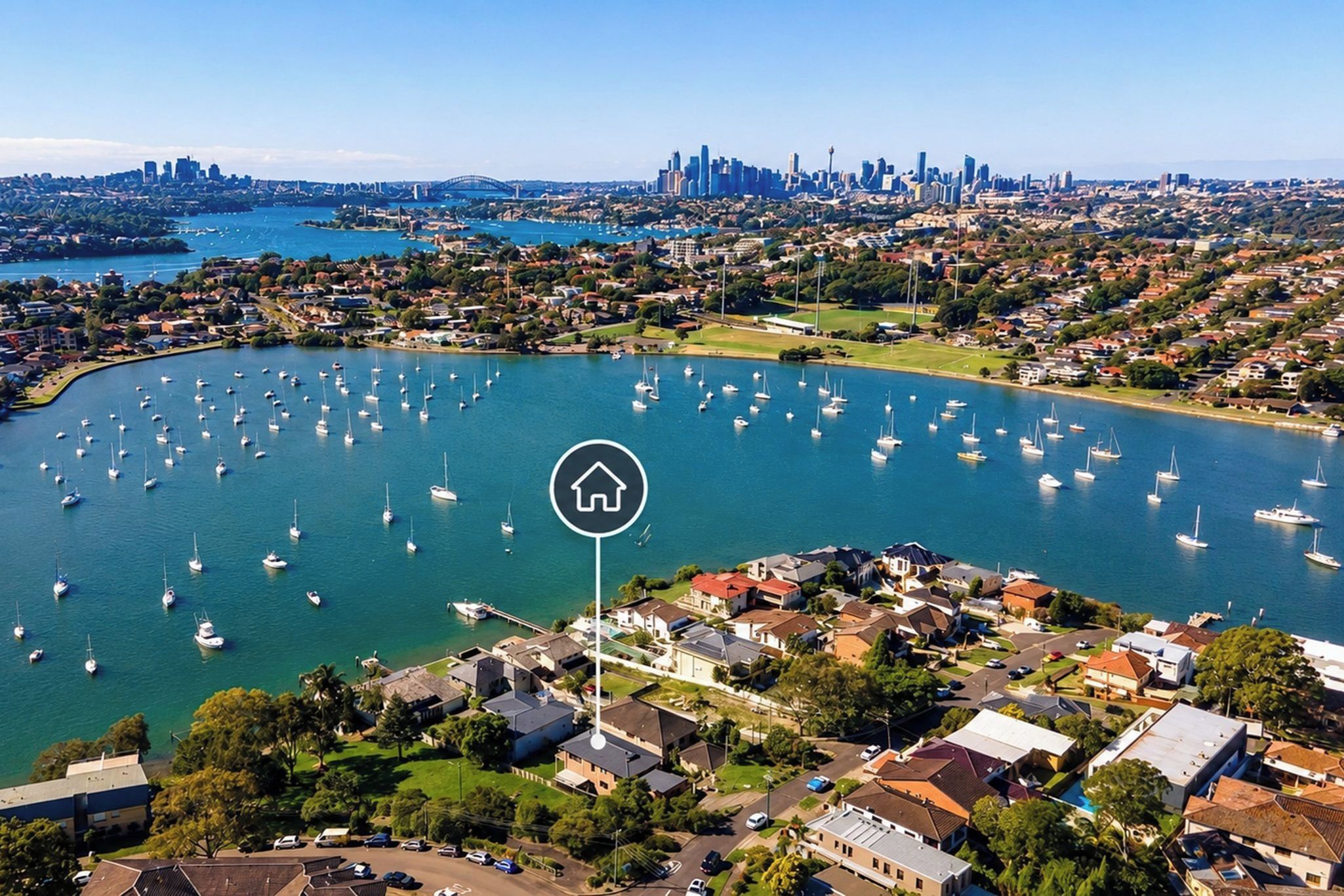 An aerial view of a coastal area with numerous boats docked in a marina, surrounded by residential buildings and a distant city skyline.