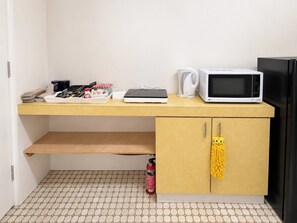 A compact kitchenette with a microwave, kettle, and a small cabinet with a yellow mop hanging on the door. - Peaceful 1BDR Private Stay in Chiswick (Chiswick)