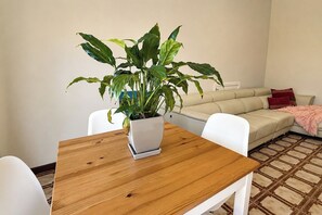 A living room with a wooden table, white chairs, a beige sofa, and a potted plant. - Peaceful 1BDR Private Stay in Chiswick (Chiswick)