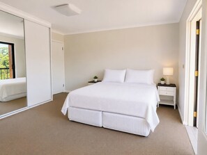 A bedroom with a large bed, a nightstand, a lamp, and a mirror. - Peaceful 1BDR Private Stay in Chiswick (Chiswick)