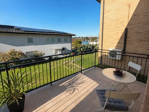 A balcony with a view of a residential area, a small table with chairs, and a potted plant. - Peaceful 1BDR Private Stay in Chiswick (Chiswick)