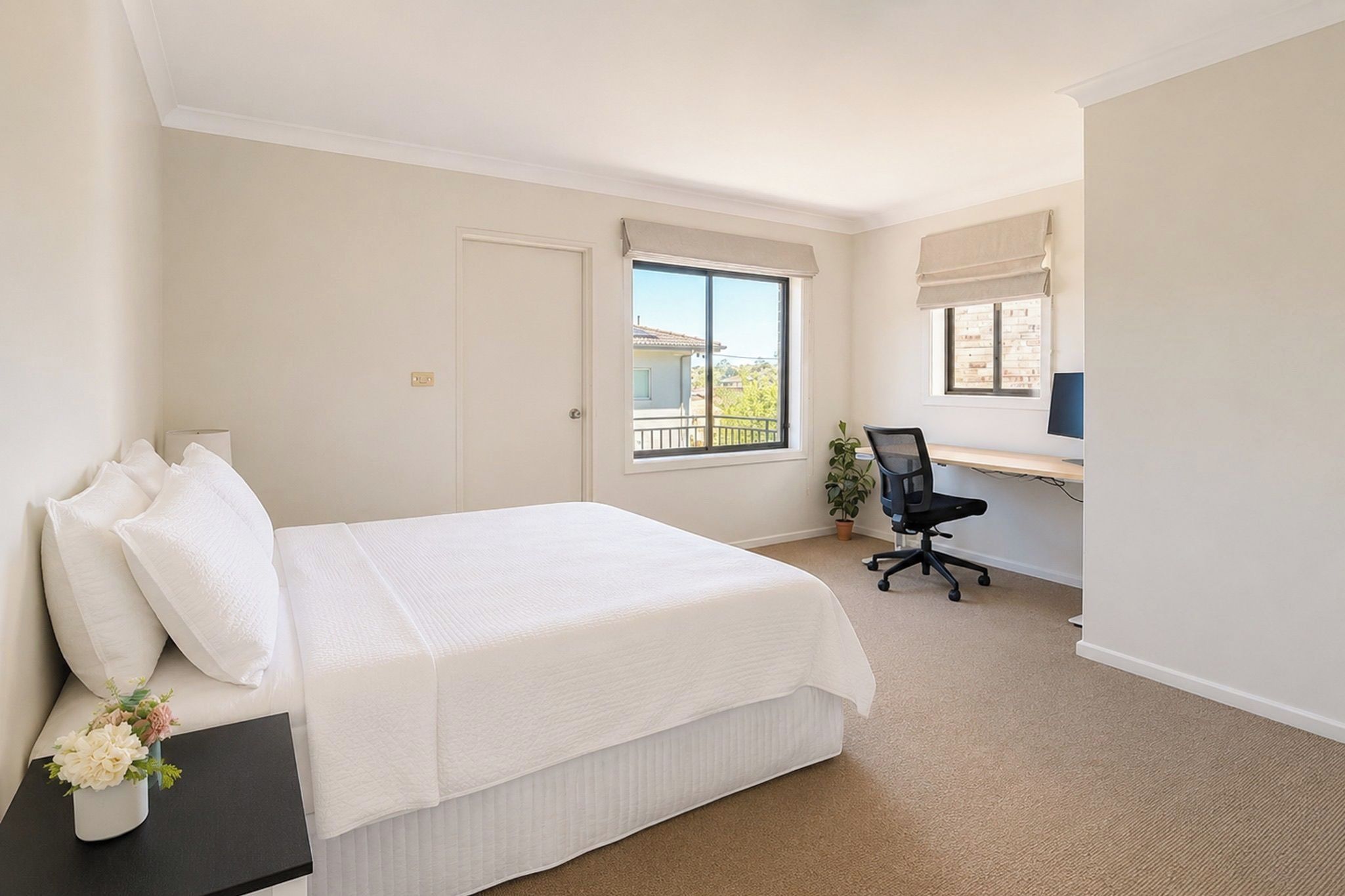 A hotel room with a bed, a desk with a chair, a window, and a view of the outside.