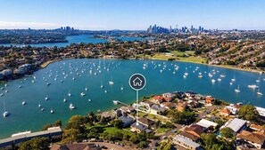 An aerial view of a marina with numerous boats, a city skyline in the background, and residential buildings nearby.