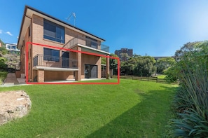 A two-story brick house with a balcony, a well-maintained lawn, and a wooden fence. - Peaceful 1BDR Private Stay in Chiswick (Chiswick)