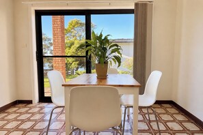 A room with a table and chairs, a potted plant, and a view through a glass door. - Peaceful 1BDR Private Stay in Chiswick (Chiswick)