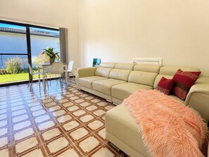A living room with a sofa, a fluffy throw, and a dining area with chairs and a table.