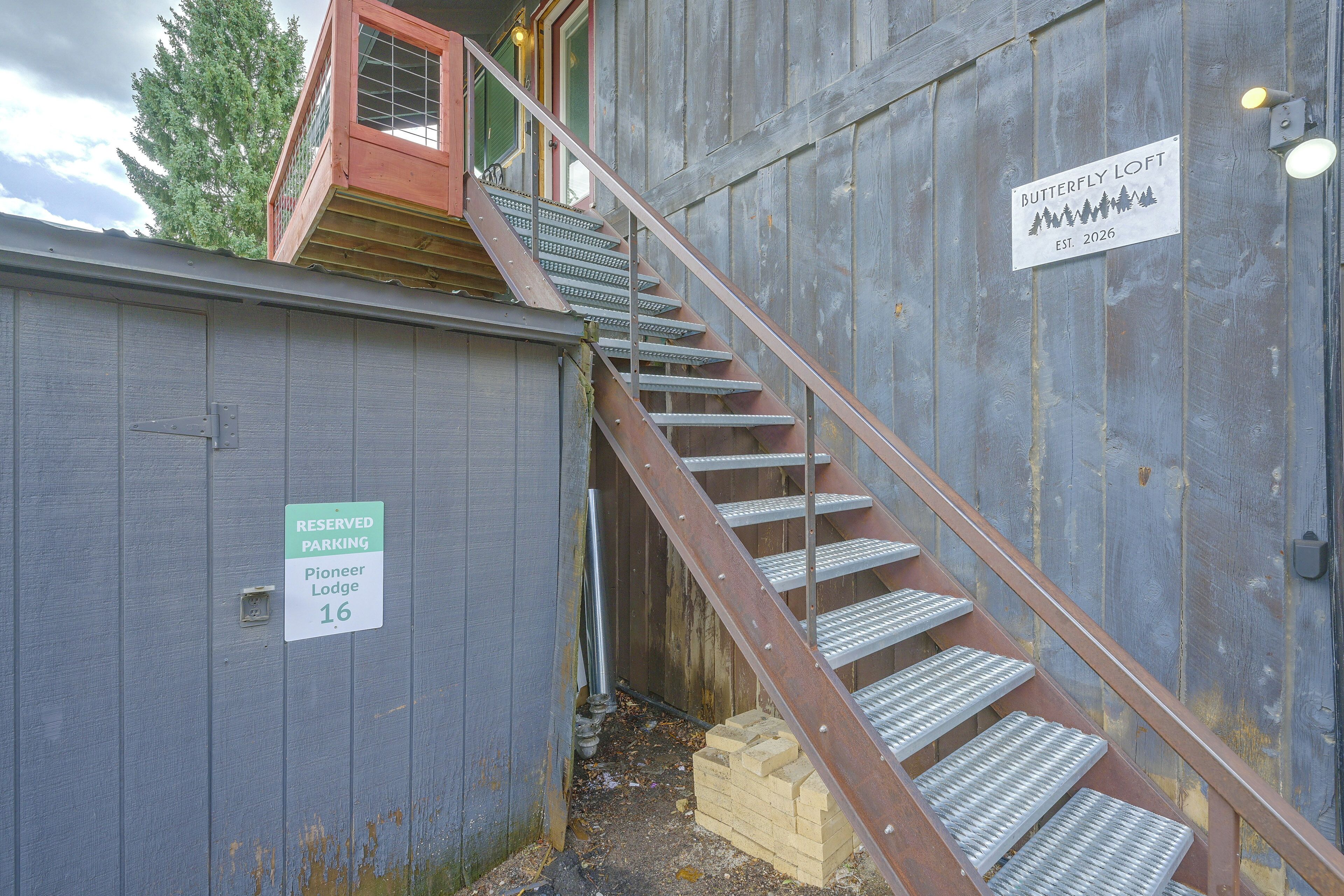 A metal staircase leading to a wooden door with a sign indicating reserved parking for Pioneer Lodge 16.