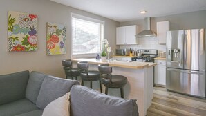 Eine moderne Küche mit einer zentralen Kochinsel, Edelstahlgeräten und einer Sitzecke mit einem grauen Sofa.