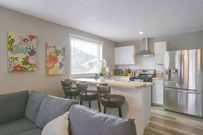 Eine moderne Küche mit einer zentralen Kochinsel, Edelstahlgeräten und einer Sitzecke mit einem grauen Sofa.