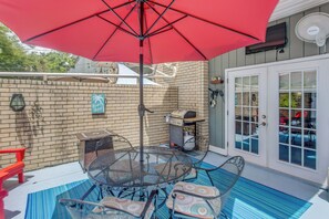 A patio with a red umbrella, a grill, and outdoor furniture. - Unwind Poolside, Walk to Ocean! Myrtle Beach Haven (Myrtle Beach)