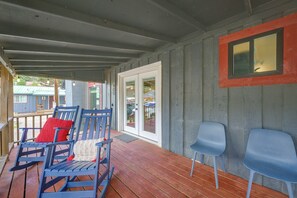 Eine überdachte Veranda mit Holzboden, blauen Stühlen und einem roten Kissen.