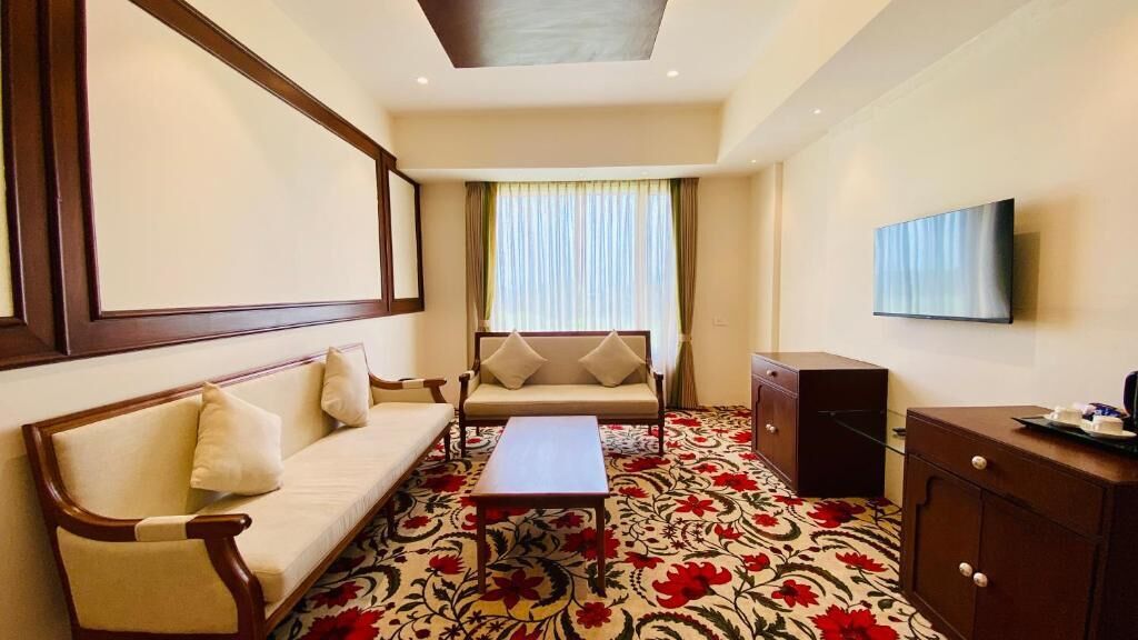 Une chambre d’hôtel équipée d’un canapé, d’une table basse, d’un téléviseur et d’un meuble.