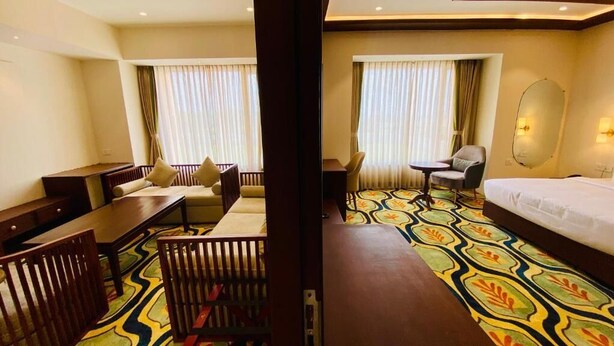 A hotel room with a bed, a desk, a chair, a small table, and a sofa.