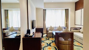 A hotel room with a sofa, a dining table, a coffee maker, and a TV. - Pukhraj Club and Resort (Ujjain)