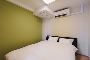 A hotel room with a bed, a wall-mounted air conditioner, and a green wall. - SERENE | Kuromon · 701 | 80 m² · 4BR · 2 shower rooms | Private Family Suite (Osaka)