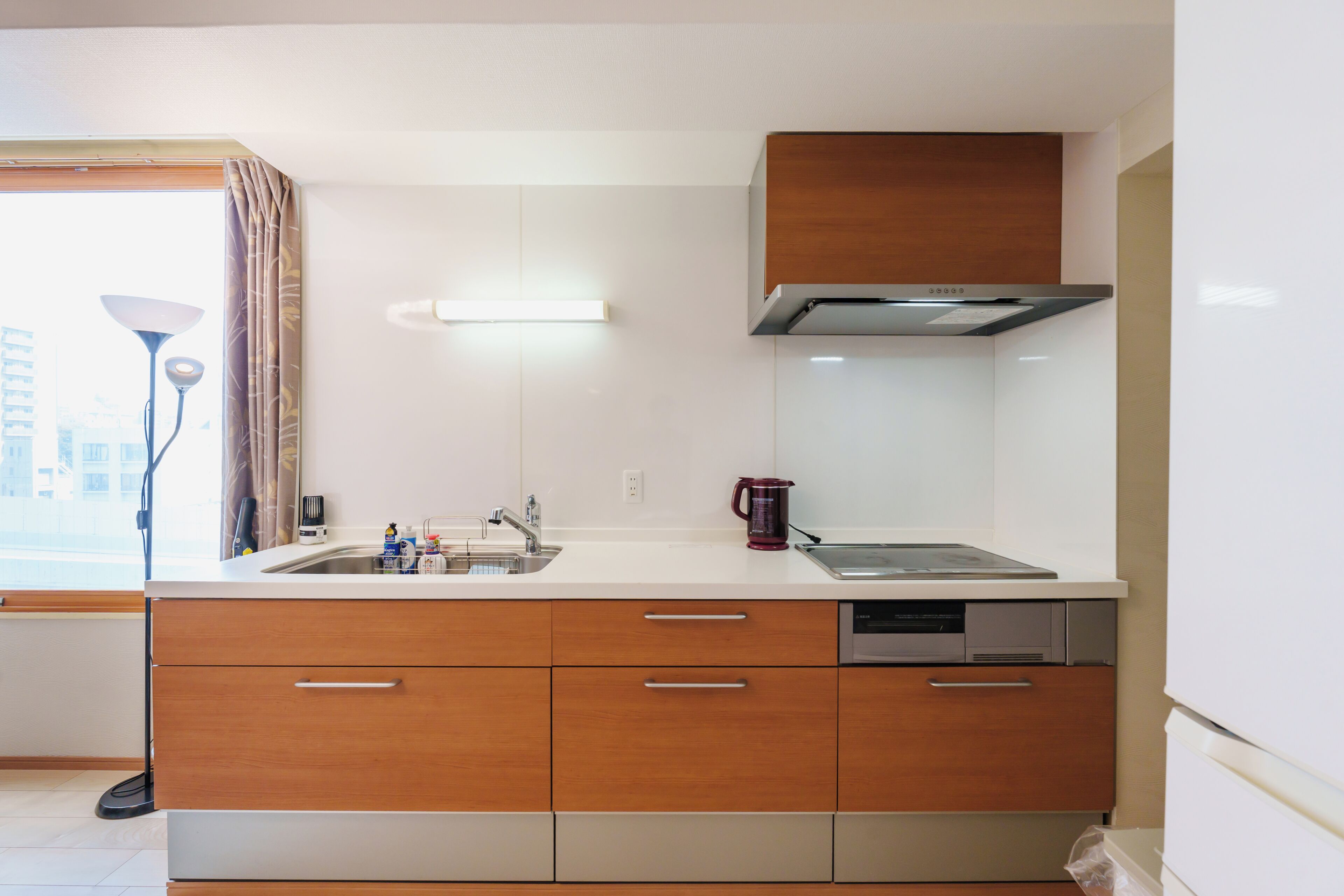 A modern kitchen with a double sink, wooden cabinets, and a stainless steel range hood.