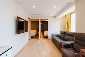 Ein modernes Hotelzimmer mit einer Couch, einem Bett und einem an der Wand befestigten Fernseher.