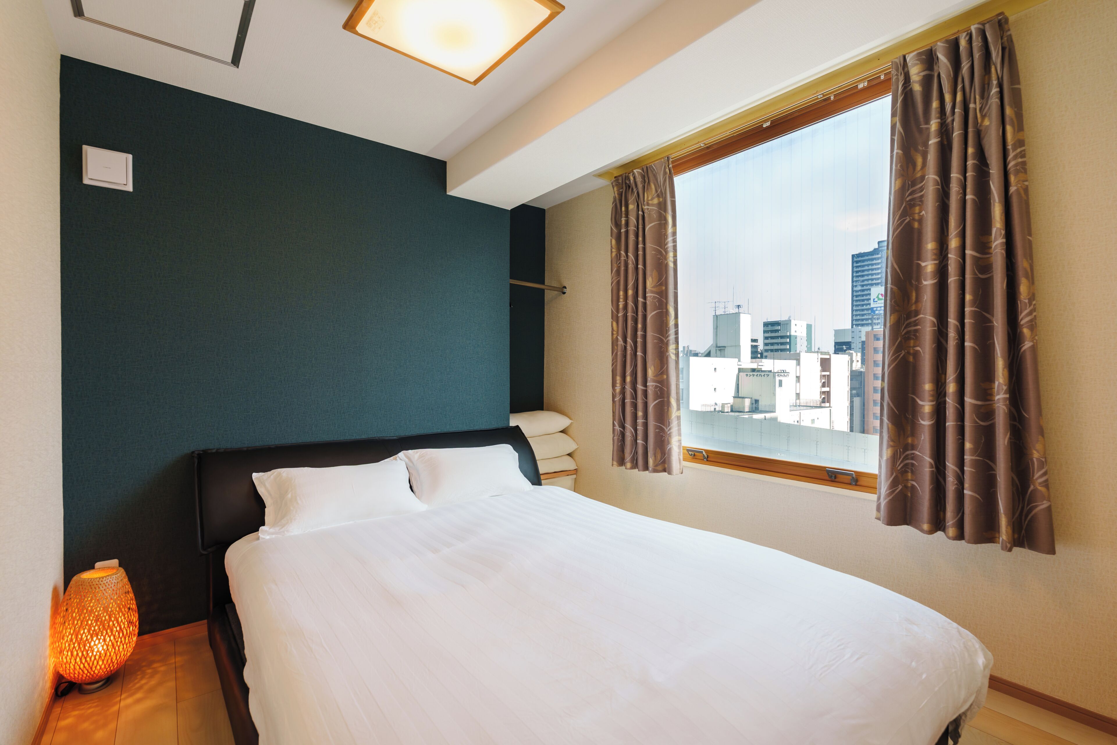 A hotel room with a bed, a nightstand, a lamp, and a window with curtains.