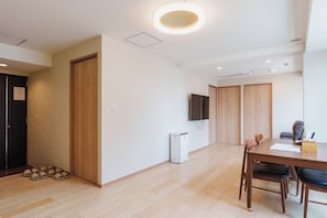 Ein modernes Interieur mit Essbereich, einer kleinen Küchenzeile und einem an der Wand montierten Fernseher.