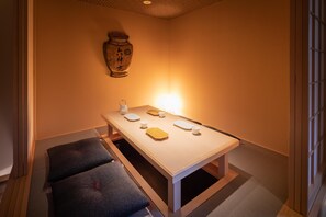 A room with a low table set for dining, a cushion, and a decorative vase on the wall. - Imakusa-so, Osaka, Dotonbori - Goyakuya - (大阪市中央区道頓堀１丁目東)