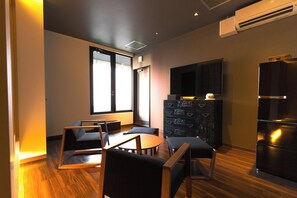 A modern living room with a flat-screen TV, a wooden cabinet, and a dining area with chairs and a table. - Imakusa-so, Osaka, Dotonbori - Goyakuya - (大阪市中央区道頓堀１丁目東)