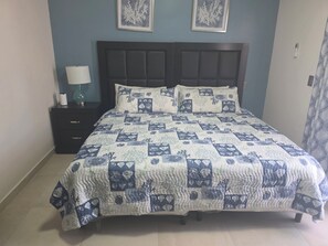 A bed with a quilt, a bedside table with a lamp, and two framed pictures on the wall. - 3-bedroom townhome in lovely Puerto Peñasco with AC comfort (Puerto Peñasco)