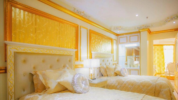 A hotel room with two beds, a large mirror, and a view of the bathroom.