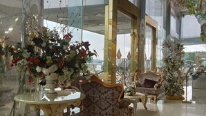 A spacious lobby with a grand chandelier, elegant furniture, and large windows offering a view of the outside.