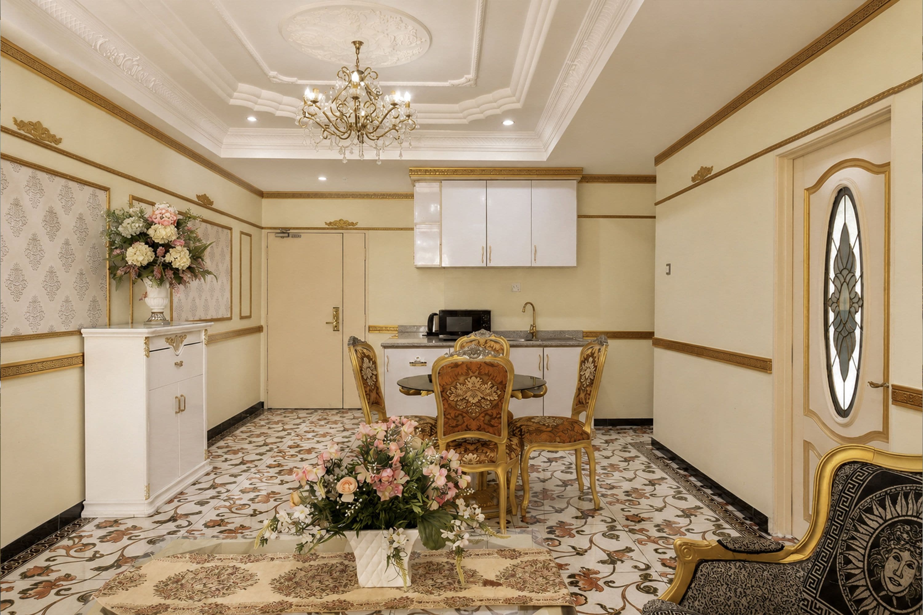 A room with a dining table, chairs, a chandelier, and a cabinet.