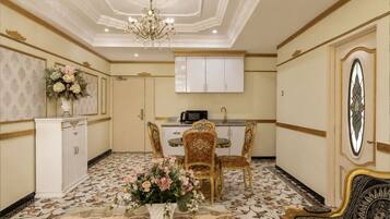 A room with a dining table, chairs, a chandelier, and a cabinet.