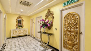 A hallway with a yellow wall, a white door with a gold design, and a sign reading 'KELUAR'.