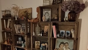 A room with wooden shelves filled with books, framed photos, and decorative items.