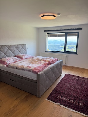A bedroom with a bed, a window with a view, a radiator, and a ceiling light. - Mountain Panorama Cabin in a Secluded Location (Oberstranach)