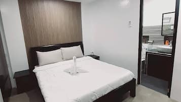 A modern bedroom with a bed, bedside tables, and a view of a bathroom through an open door.