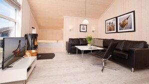 Una sala de estar moderna con televisor, sofá, mesa de centro y lámpara colgante.