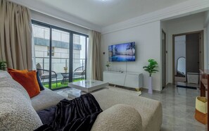 A modern living room with a sofa, a coffee table, and a flat-screen TV mounted on the wall. - Cozy Nest 1BR Kilimani (Nairobi)