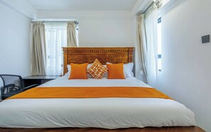 A hotel room with a large bed, a wooden headboard, and a desk with a chair. - Cozy Nest 1BR Kilimani (Nairobi)