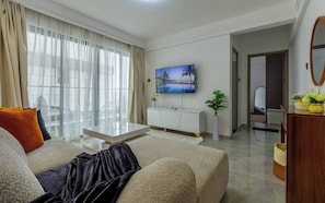 A modern living room with a sofa, a coffee table, a flat-screen TV mounted on the wall, and a potted plant. - Cozy Nest 1BR Kilimani (Nairobi)