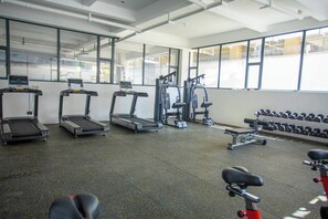 A gym with treadmills, weight machines, and dumbbells. - Cozy Nest 1BR Kilimani (Nairobi)