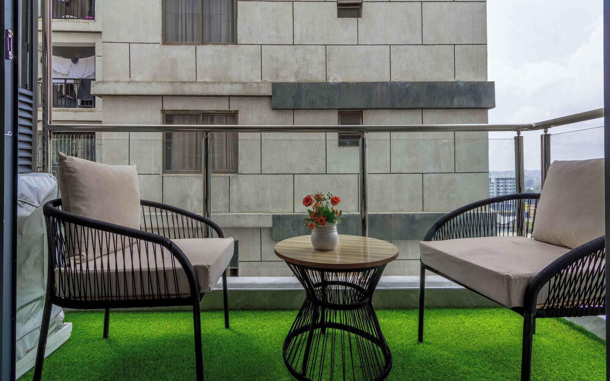 A balcony with two chairs, a small table, and a vase of flowers.