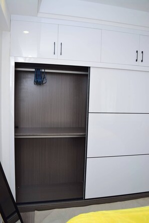 A room with a white wardrobe, two drawers, and a shelf. - Cozy Nest 1BR Kilimani (Nairobi)