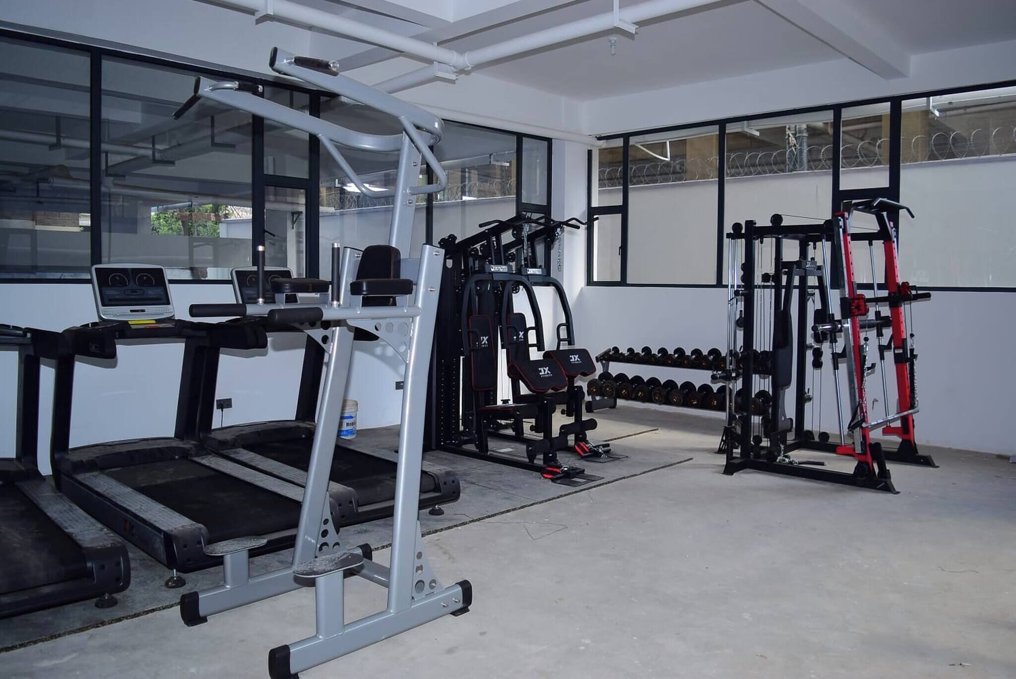 A gym with treadmills, weight machines, and dumbbells.