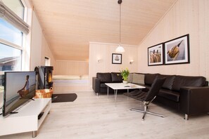 Ein modernes Wohnzimmer mit Sofa, Couchtisch, Fernseher und Kamin.