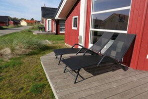 A red building with a wooden deck and two black lounge chairs. - 6-gaste-aufenthalt an der Skandinavischen Kuste (Grossenbrode)
