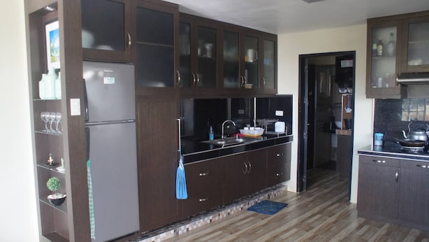 A modern kitchen with dark cabinetry, a stainless steel refrigerator, and a black countertop.