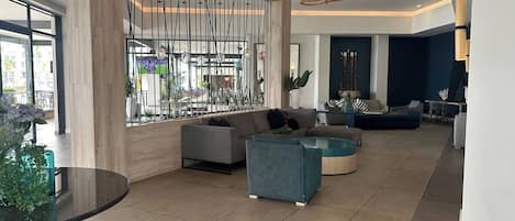 A spacious lobby with a seating area, a large window, and a modern chandelier.