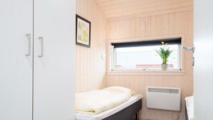 A bedroom with a bed, a window with a plant, a radiator, and a white wardrobe. - Grobenbrode House in der Nähe von Shore (Großenbrode)